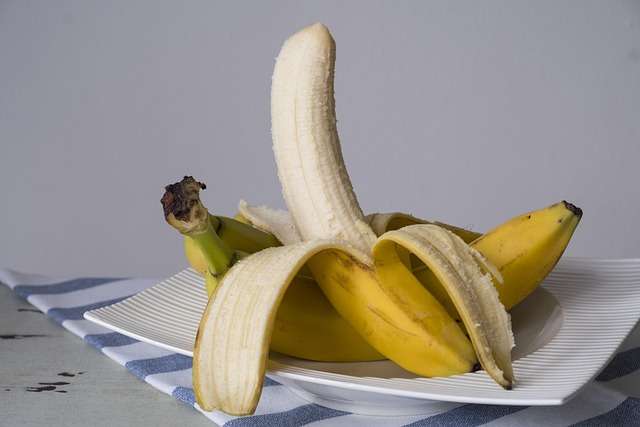 "Banana-prata cortada em rodelas uniformes sobre uma taça de iogurte com aveia, ilustrando uma opção de pequeno-almoço saudável."