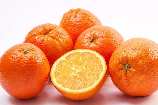"Laranja-bahia cortada ao meio mostrando a polpa suculenta, cor de laranja viva e sem sementes sobre uma mesa de madeira."