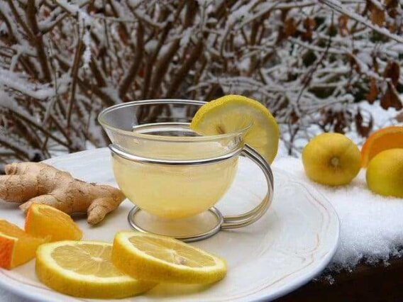 Suco de Limão com Gengibre: Energia e Queima de Gordura 5 "Copo de vidro com suco de limão com gengibre, decorado com folhas de hortelã e rodelas de limão sobre uma mesa de madeira."