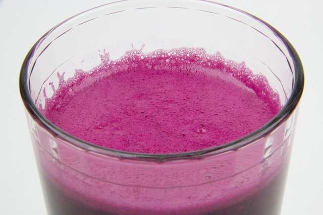  "Copo com suco de beterraba natural, apresentando uma cor carmesim intensa e uma leve espuma avermelhada no topo."