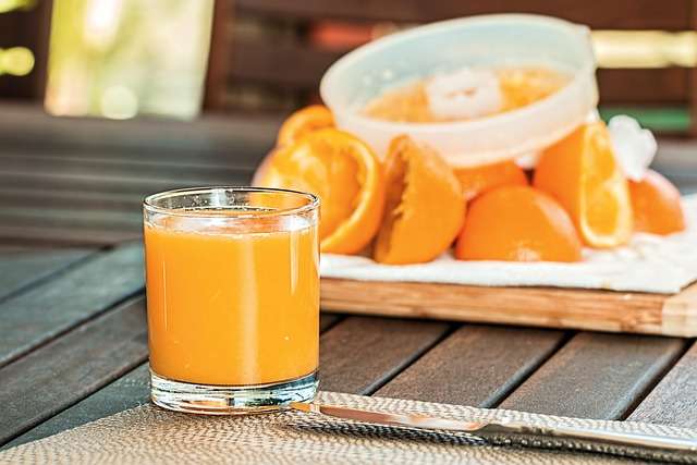 "Copo com suco de laranja natural e fresco, com polpa visível e uma leve espuma no topo."