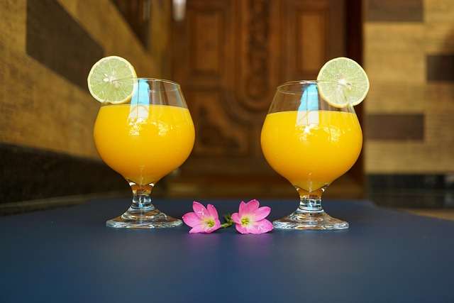 "Suco de manga em um copo decorado com uma fatia da fruta na borda e gelo."