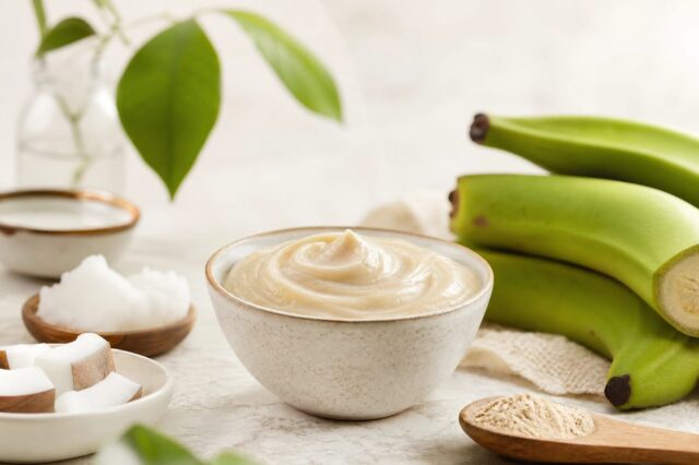 Biomassa de banana verde cremosa, de cor bege clara, armazenada em um pote de vidro transparente sobre uma bancada de cozinha