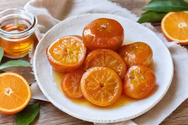 Frasco de vidro transparente fechado hermeticamente com compota artesanal de laranja-da-terra, exibindo a calda brilhante e a textura das cascas.